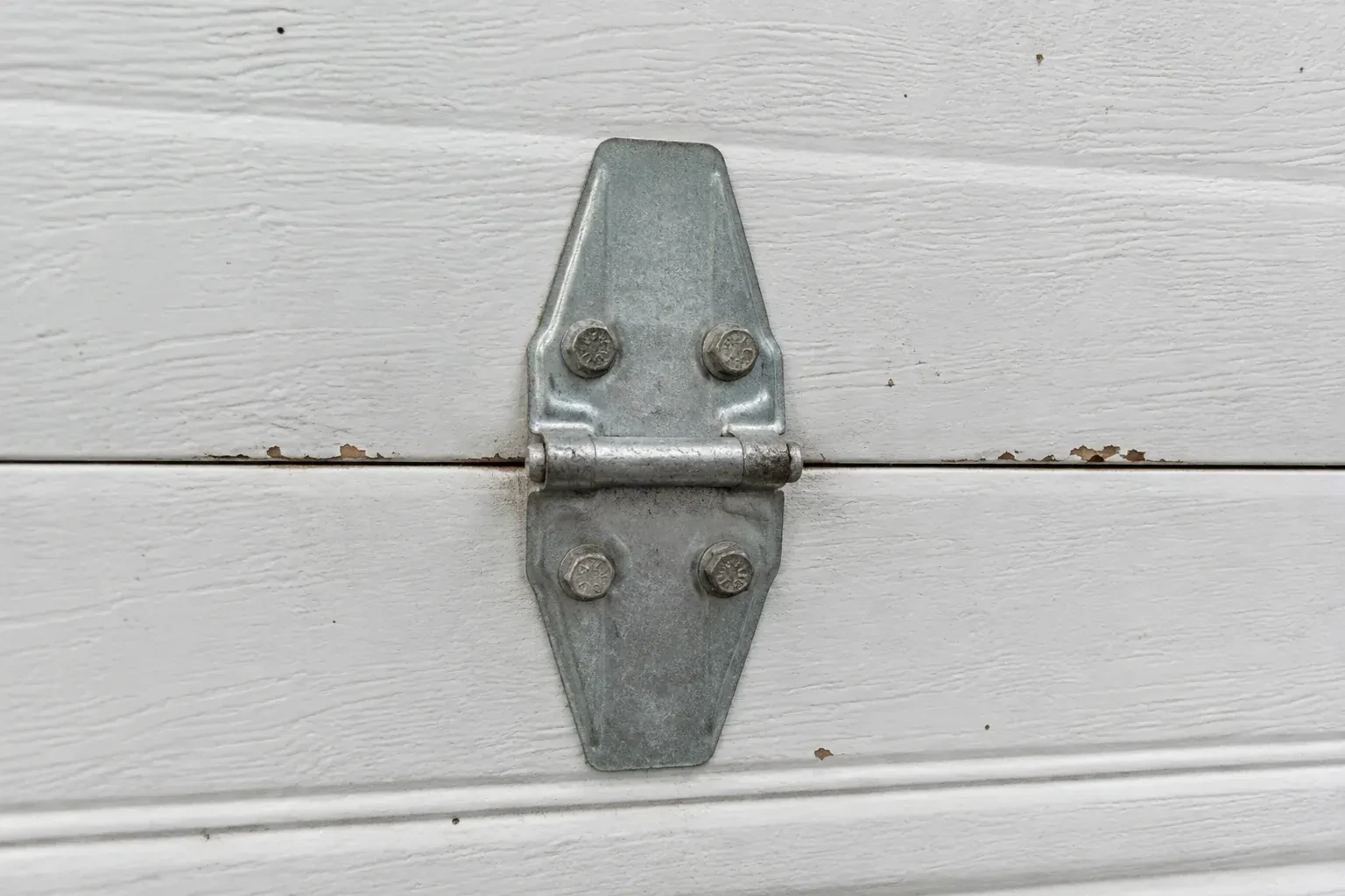 Metal center hinge across a seam in a white sectional garage door. — Garage Door Hinge Replacement, Whitchurch-Stouffville